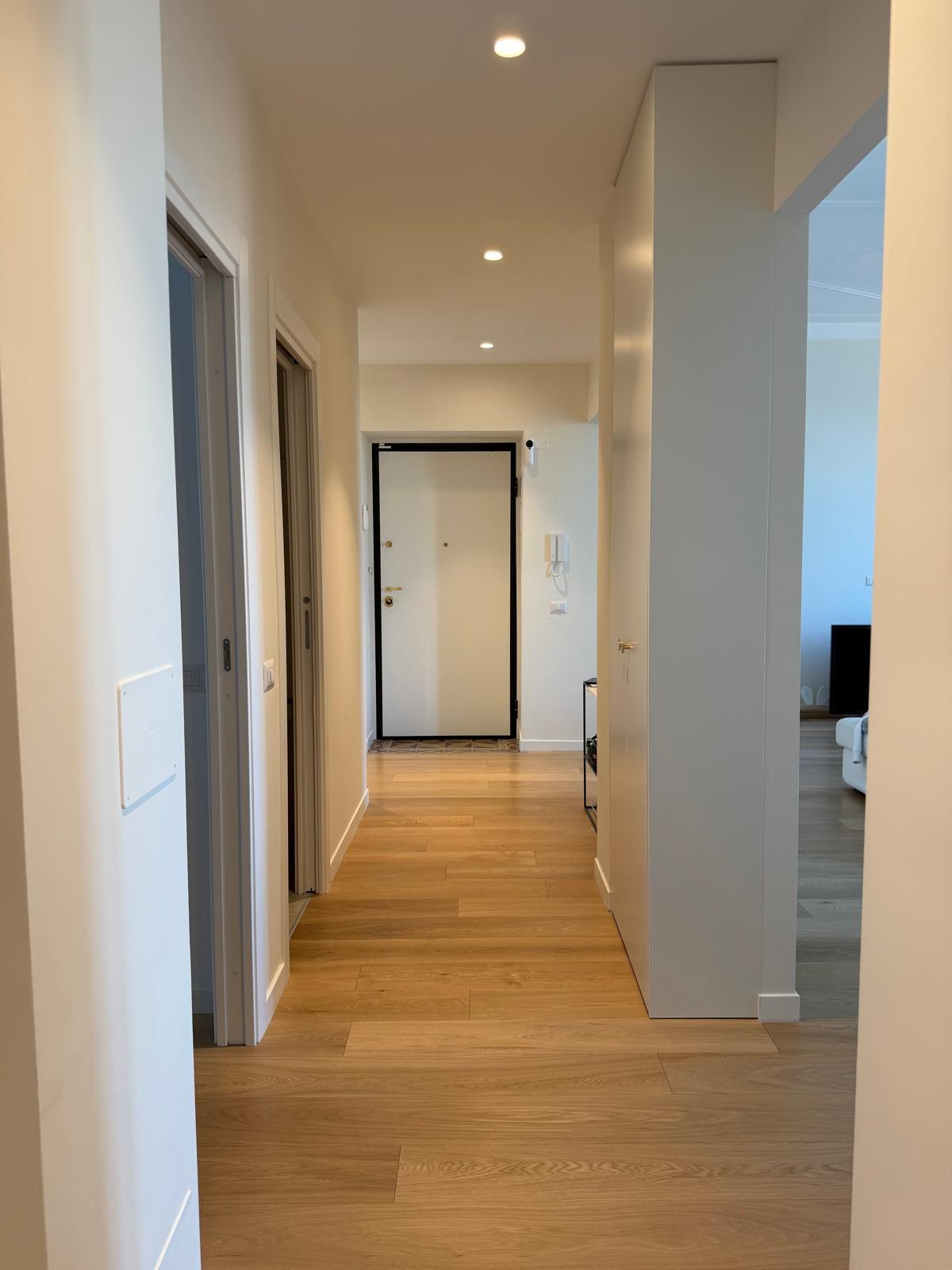 Corridoio residenziale con pavimento in legno e illuminazione a incasso